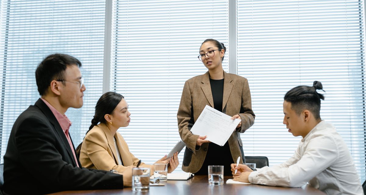 商务会议中女士站立向团队做方案演示